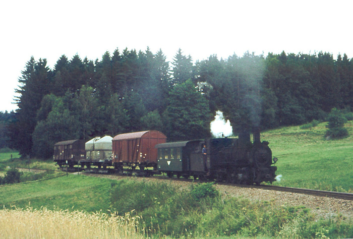 399.04 mit einem der typischen und schwer aussehenden Güterzüge nahe der Schleife bei Weitra, fotografiert im Juli 1976