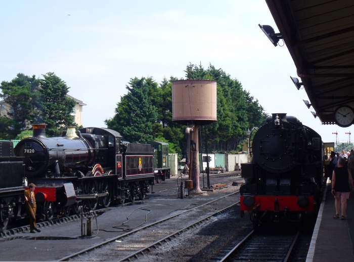 Rechts ist 6046 ist mit ihrem Zug von Bishops Lydeard eingetroffen, links sieht man in Mi‍n‍ehead  die 7820 DINMORE MANOR (hinter dem Tender der 7822 FOXCOTE MANOR) stehen, fotografiert um 13:50h am 26.07.2018