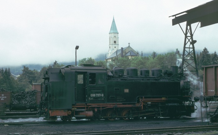 099 737 (99 772) im Bw Oberwiesenthal, im Hintergrund die markante Kirche des Ortes, um 15:10h bei leider ziemlich unfotogenem Wetter am 12.09.1993