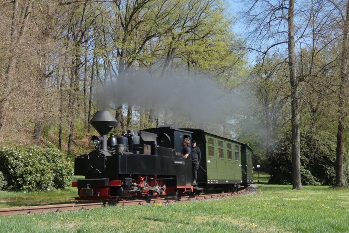99 3317 mit Zug Richtung Weißwasser im Park hinter Ausfahrt Bad Muskau nahe der Bautzener Straße (B115), um 10:49h am 20.04.2025