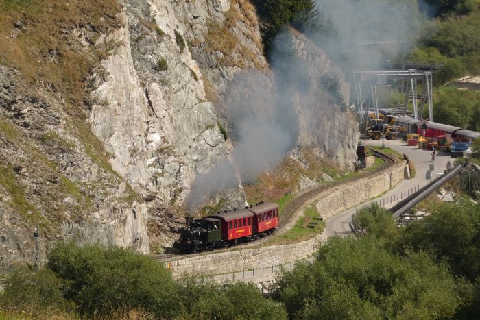 Nr.6 WEISSHORN mit 2-Wagen-Sonderzug nach Tiefenbach, in den Kurven an den Felsen im Furka-Reuss-Tal hinter dem Betriebswerk Realp, um 10:42h am 14.08.2022