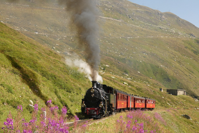 704&nbsp; mit Zug Nr.133 Realp->Oberwald weit unterhalb vom Bahnhof Furka und wenige hundert Meter hinter der Brücke über den Sidelenbach, um 11:03h am 13.08.2026