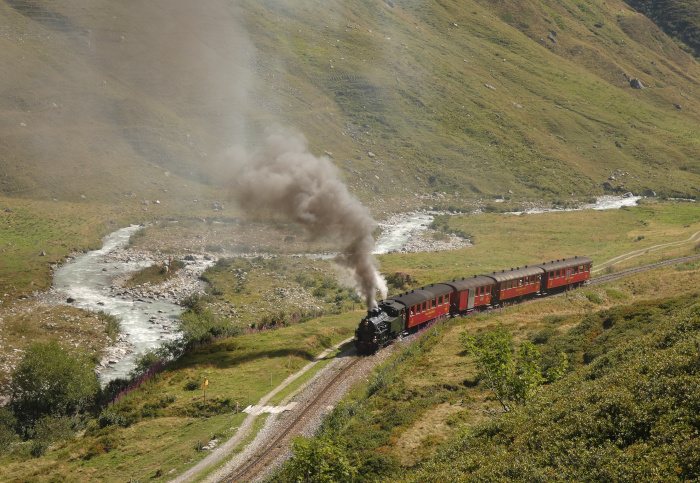 Lok 704 mit Zug Nr.133 Realp&rarr;Oberwald, aufgenommen und fotografiert im Furkareusstal hinter dem Hp Tiefenbach kurz hinter dem Beginn der Zahnstange, um 10:46h am 14.08.2026