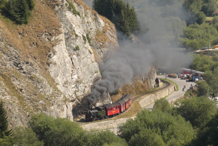 Lok 704 mit Zug 133 Realp&rarr;Oberwald im Furkareusstal unten kurz hinter dem DFB-Betriebswerk, um 10:25 am 15.08.2026