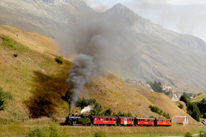 Lok 704 mit Zug 133 Realp&rarr;Oberwald wenige hundert Meter nach Beginn der Zahnstange und kurz vor den Wilerbrücken, um 10:23h am 16.08.2026