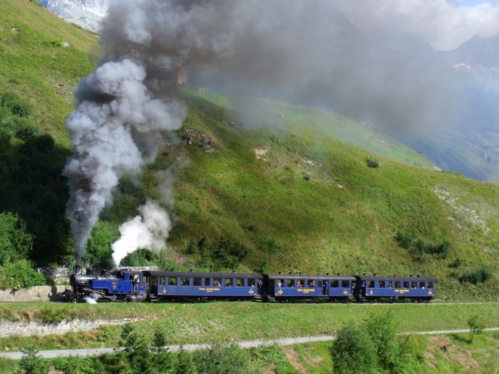 DFB 1 mit erstem Zug des Tages von Realp nach Oberwald, fotografiert und akustisch aufgenommen am Beginn des Zahnstangenabschnitts (weit hinten auf dem Foto sichtbar!), kurz vor den Brücken über die Furkareuss (Straße und Bahn direkt nebeneinander), um 10:29h am 22.08.2014