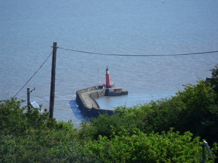 In der Gegenrichtung (Nordosten) kann man einen Teil von Watchet Hafen sehen, nämlich die alte Kaimauer mit dem Leuchtturm am Ende, 
													fotografiert am 06.08.2016 um etwa 10:15h.